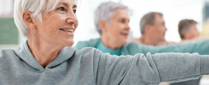 Assisted living works: seniors stretch arms during a group wellness class in a bright room