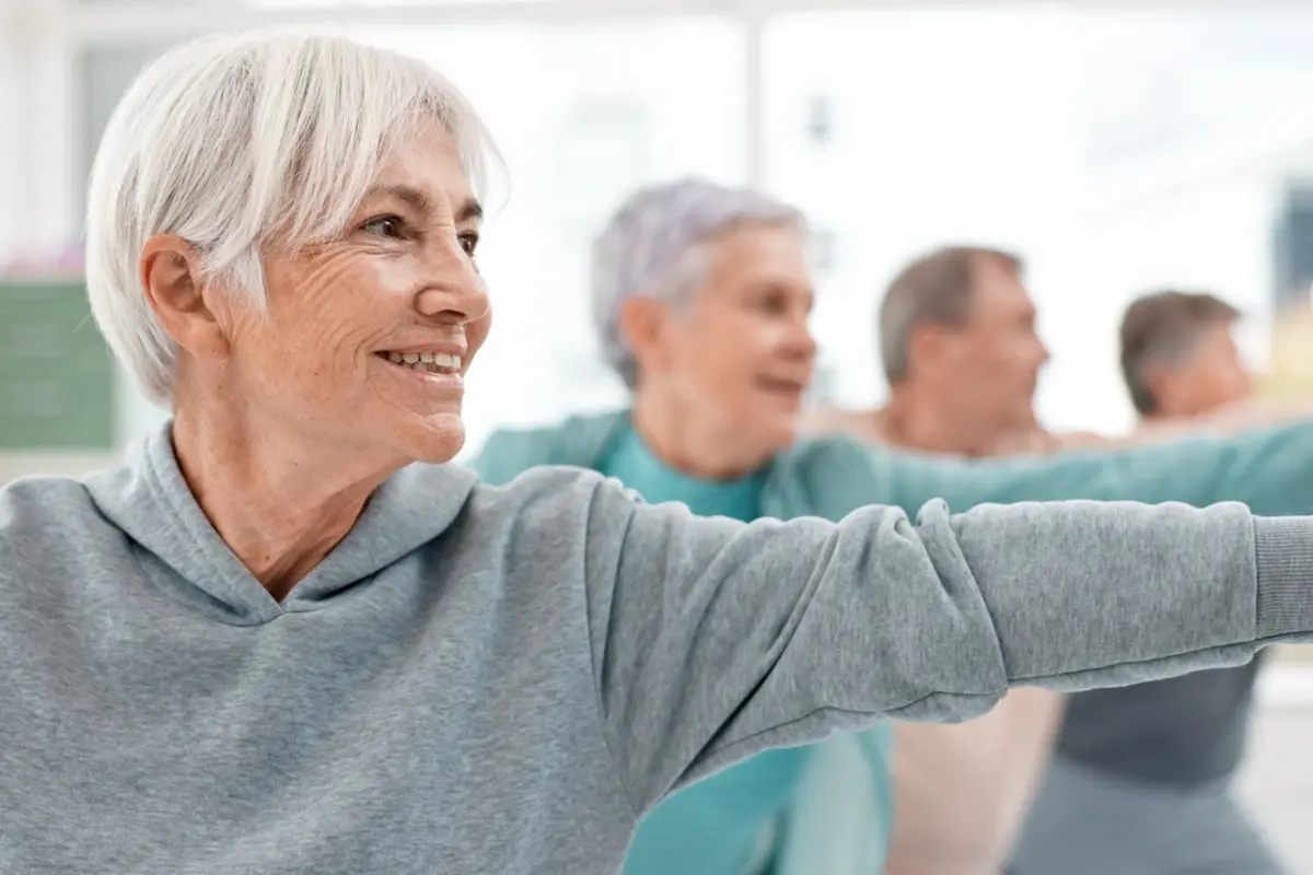 Assisted living works: seniors stretch arms during a group wellness class in a bright room